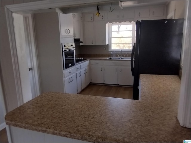 kitchen with white cabinetry, sink, black refrigerator, and oven