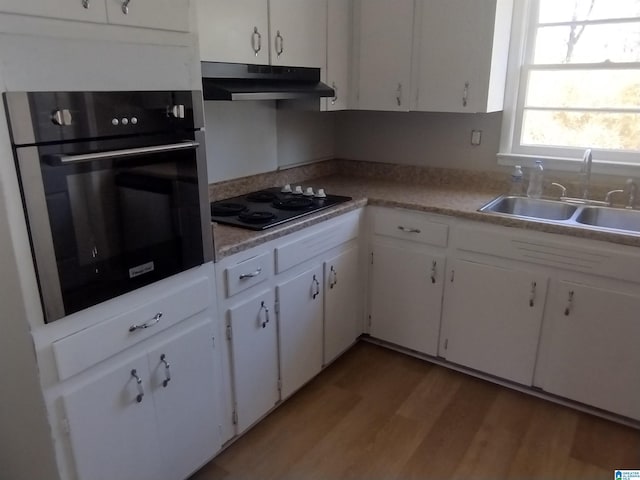 kitchen featuring white cabinets, sink, oven, and black stovetop