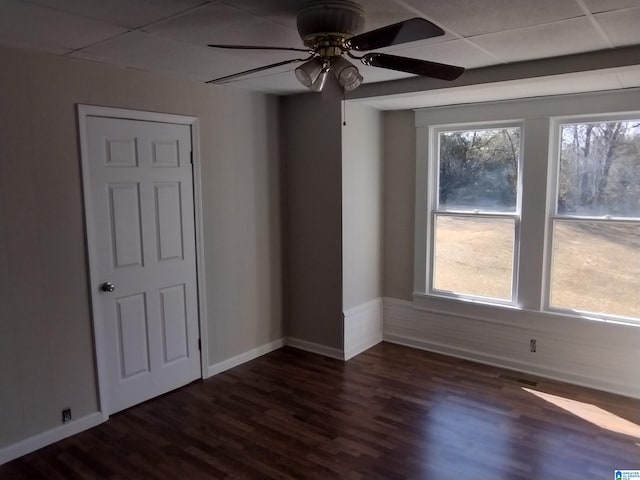 empty room featuring ceiling fan, a paneled ceiling, and dark hardwood / wood-style flooring