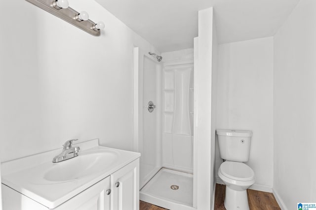 bathroom featuring a shower, hardwood / wood-style floors, vanity, and toilet