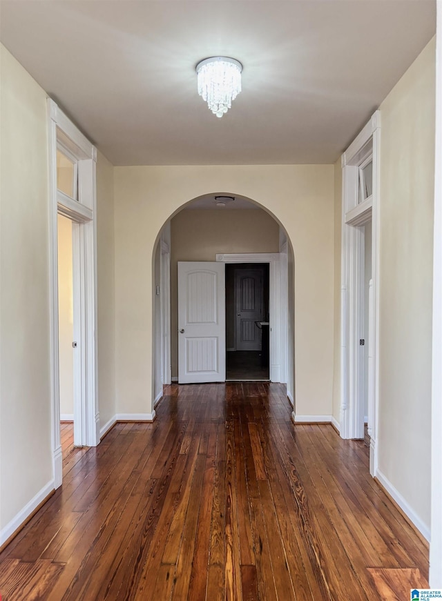 hall with dark hardwood / wood-style floors and a notable chandelier