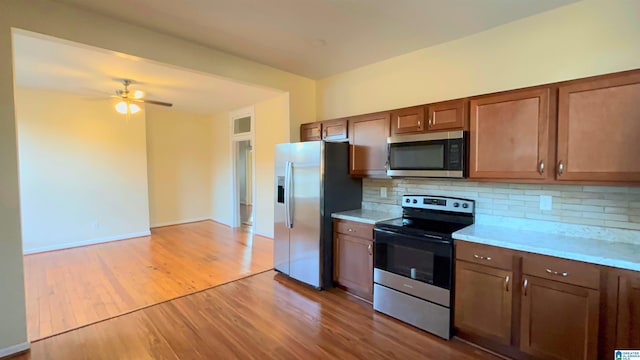 kitchen featuring backsplash, ceiling fan, appliances with stainless steel finishes, and light wood-type flooring