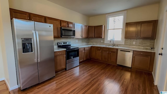 kitchen featuring appliances with stainless steel finishes, dark hardwood / wood-style flooring, sink, and backsplash