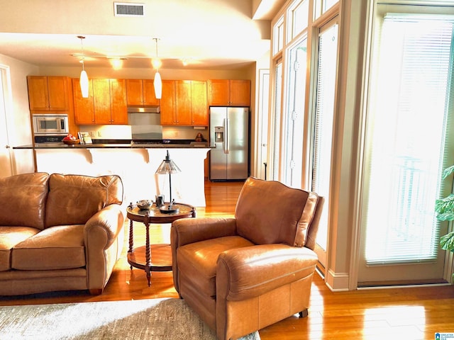 interior space featuring stainless steel appliances, a breakfast bar, pendant lighting, and light wood-type flooring