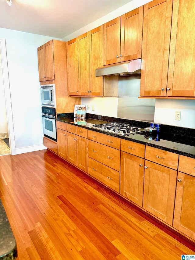 kitchen featuring dark stone countertops, hardwood / wood-style floors, and appliances with stainless steel finishes