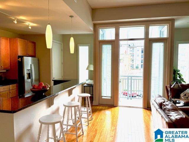 kitchen with stainless steel refrigerator with ice dispenser, a breakfast bar, pendant lighting, and light hardwood / wood-style flooring