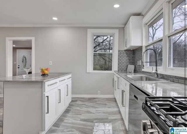 kitchen with sink, appliances with stainless steel finishes, a wealth of natural light, light stone countertops, and white cabinets