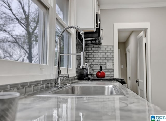 kitchen featuring white cabinetry, backsplash, light stone counters, and a wealth of natural light