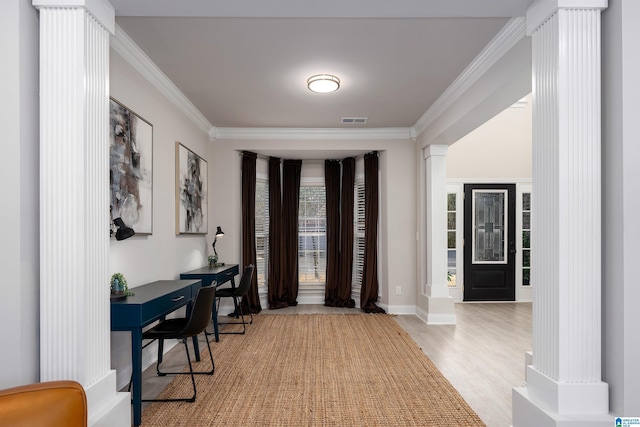 foyer entrance featuring crown molding, decorative columns, and light wood-type flooring