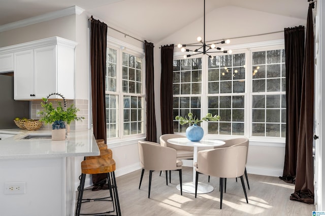 dining area with an inviting chandelier, sink, vaulted ceiling, and light wood-type flooring