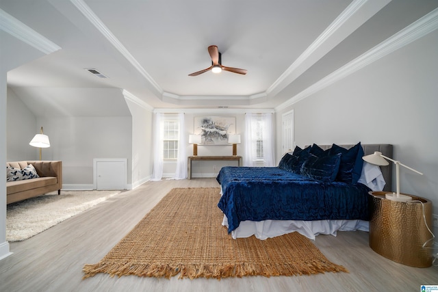 bedroom featuring crown molding, ceiling fan, a raised ceiling, and light wood-type flooring