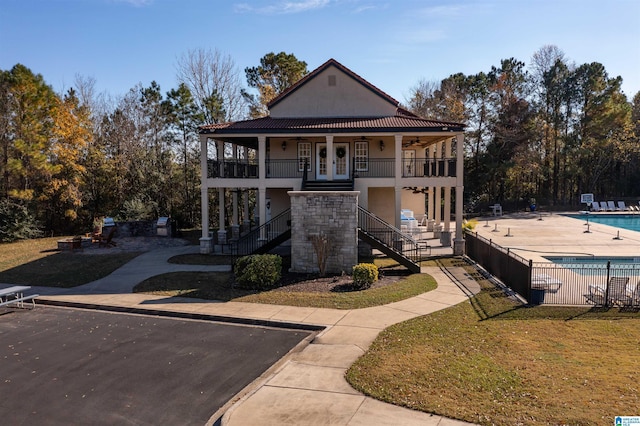 view of front of property featuring ceiling fan, a community pool, a patio area, french doors, and a balcony