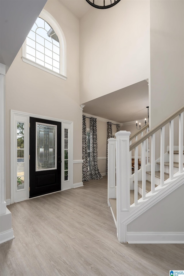 entrance foyer with a notable chandelier, light hardwood / wood-style flooring, and a high ceiling