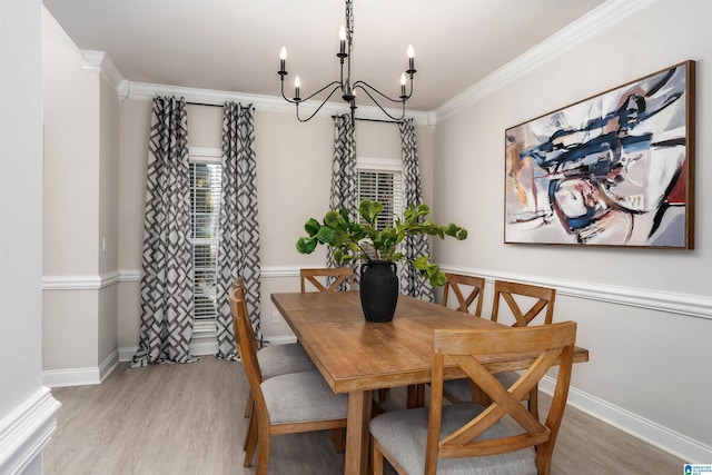 dining space with a notable chandelier, crown molding, and light hardwood / wood-style flooring