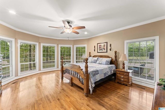 bedroom featuring multiple windows, ornamental molding, and light hardwood / wood-style floors