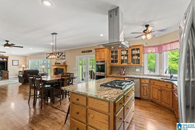 kitchen featuring sink, tasteful backsplash, appliances with stainless steel finishes, a kitchen island, and island exhaust hood