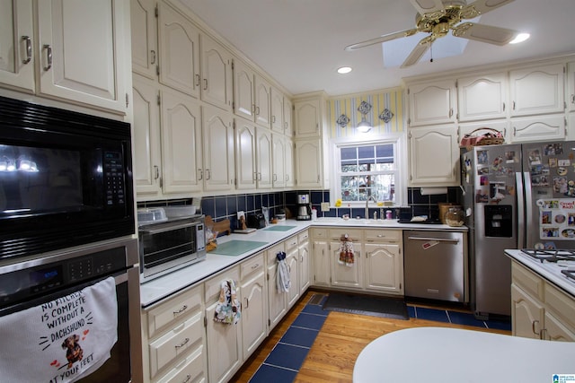 kitchen with sink, backsplash, ceiling fan, stainless steel appliances, and dark wood-type flooring