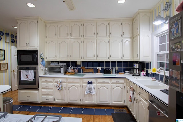 kitchen featuring black microwave, sink, dishwashing machine, oven, and decorative backsplash