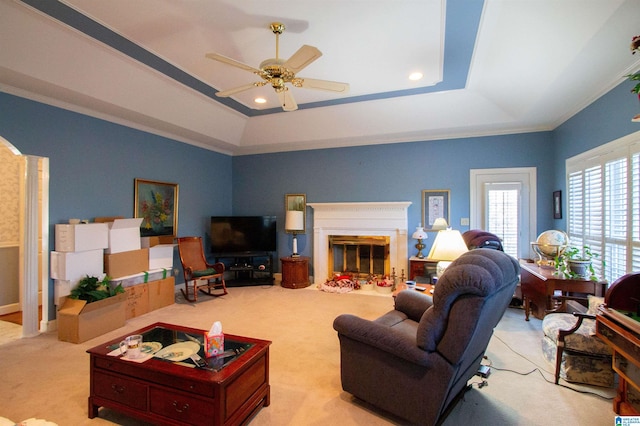 living room with ceiling fan, light colored carpet, ornamental molding, and a raised ceiling