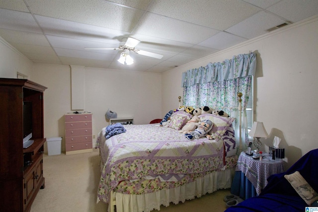 carpeted bedroom with crown molding, a drop ceiling, and ceiling fan