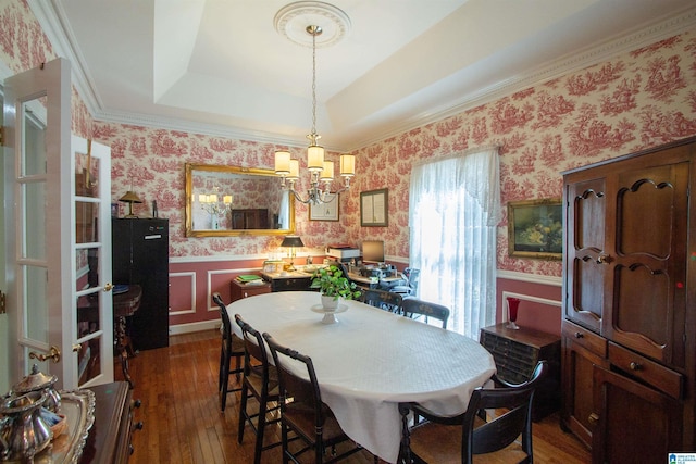 dining area featuring dark hardwood / wood-style flooring, a raised ceiling, and a chandelier