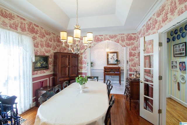 dining space with hardwood / wood-style flooring, a raised ceiling, and a chandelier