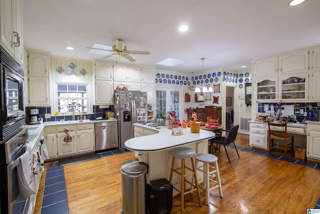 kitchen with a breakfast bar area, a skylight, a center island, hanging light fixtures, and stainless steel appliances