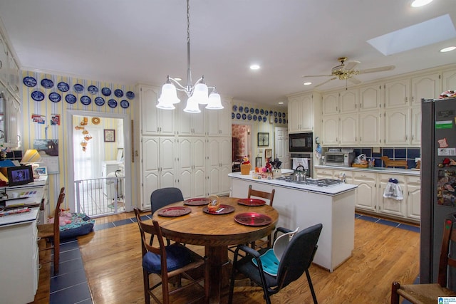 kitchen featuring pendant lighting, a skylight, stainless steel appliances, light hardwood / wood-style floors, and a kitchen island