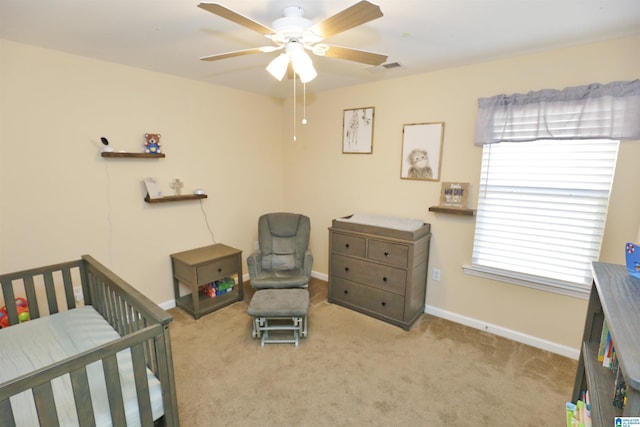 bedroom featuring light carpet, a crib, and ceiling fan