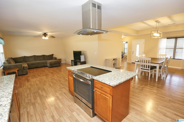 kitchen featuring decorative light fixtures, island exhaust hood, electric range, light hardwood / wood-style floors, and light stone counters