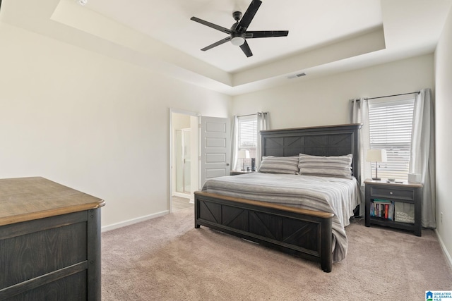 carpeted bedroom with a raised ceiling and ceiling fan