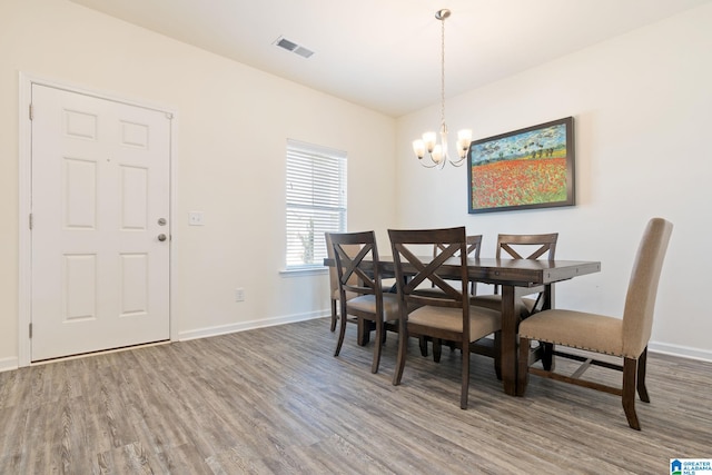 dining space with wood-type flooring and a notable chandelier