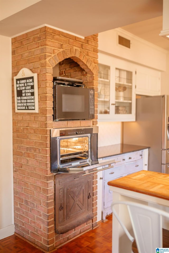 kitchen featuring butcher block counters, stainless steel appliances, and white cabinets