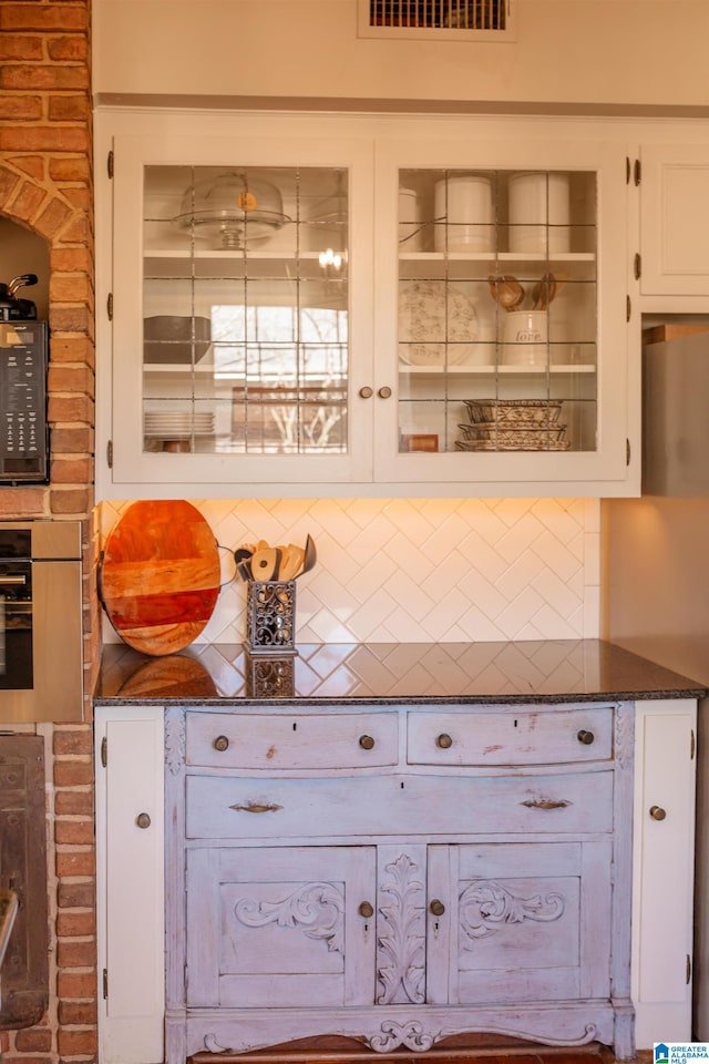 kitchen featuring white cabinetry, decorative backsplash, and dark stone countertops