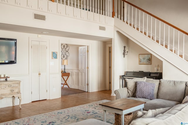 living room with a towering ceiling and tile patterned floors