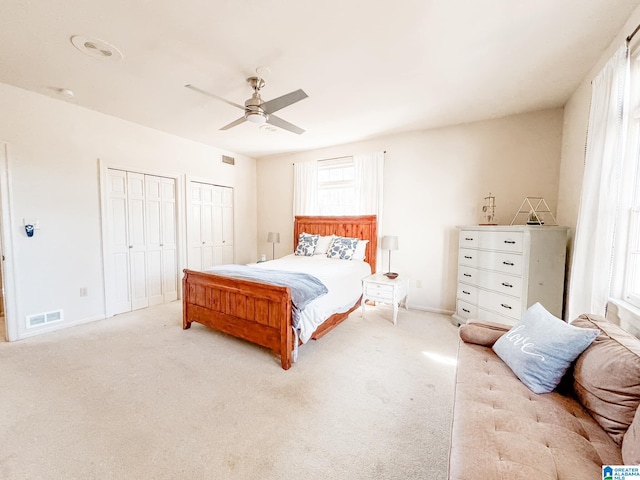 carpeted bedroom featuring ceiling fan and multiple closets