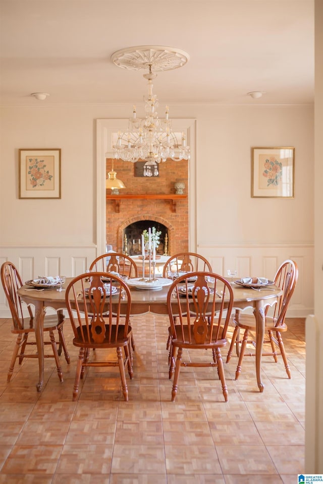 tiled dining room featuring ornamental molding, a chandelier, and a brick fireplace