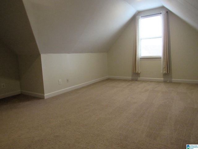 additional living space featuring lofted ceiling and light carpet