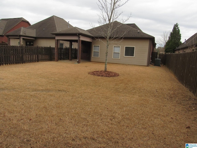 rear view of house featuring cooling unit and a yard