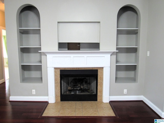 room details featuring a tiled fireplace, hardwood / wood-style floors, and built in features