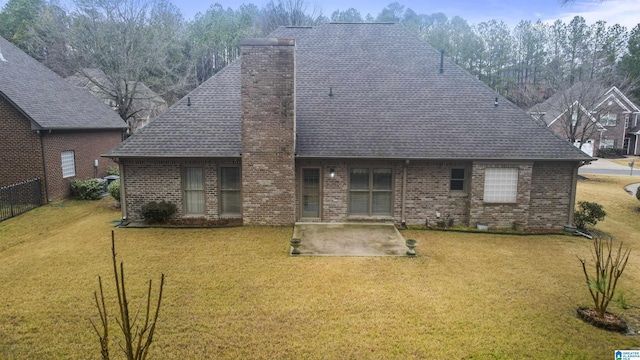 rear view of house with brick siding, a patio, a chimney, a lawn, and fence