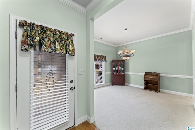 entryway with ornamental molding, carpet, a notable chandelier, and baseboards