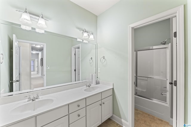 bathroom featuring double vanity, enclosed tub / shower combo, a sink, and tile patterned floors