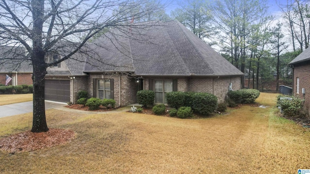 view of front facade featuring a garage, a shingled roof, brick siding, driveway, and a front lawn