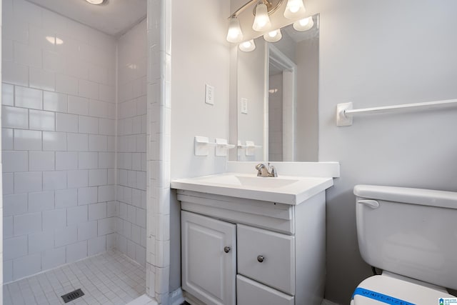 bathroom with vanity, toilet, and a tile shower