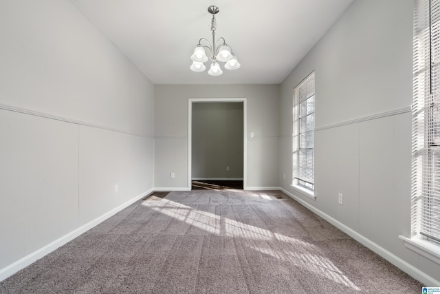 carpeted empty room featuring an inviting chandelier