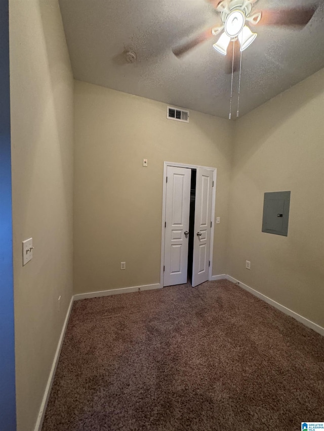 empty room featuring ceiling fan, electric panel, carpet floors, and a textured ceiling