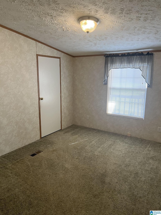 unfurnished room with crown molding, carpet floors, and a textured ceiling