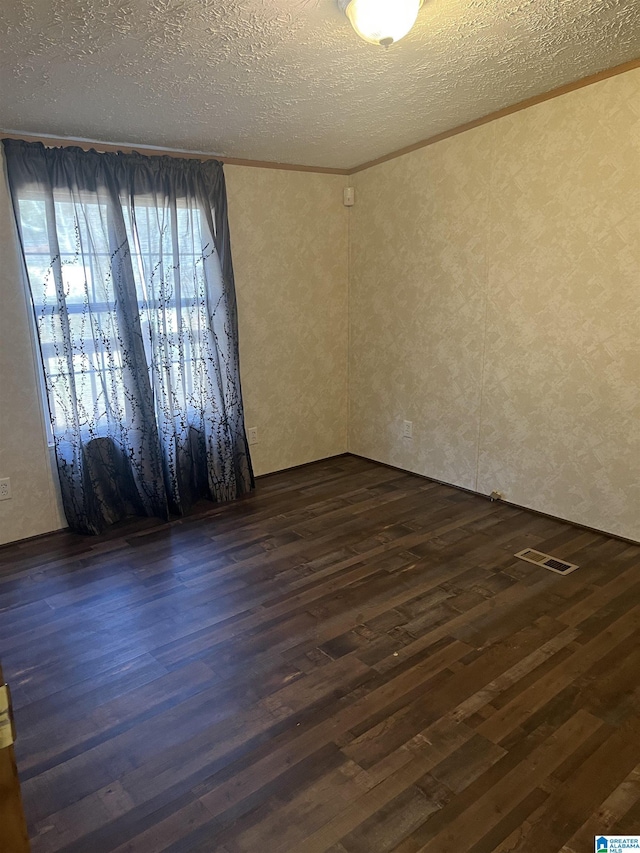 spare room with crown molding, dark hardwood / wood-style floors, and a textured ceiling