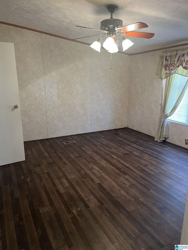 empty room with crown molding, dark hardwood / wood-style floors, and a textured ceiling